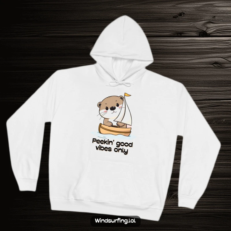 Funny otter peeking from behind a sailboat on a cozy hoodie, embodying gentle curiosity and a love for sailing escapades.