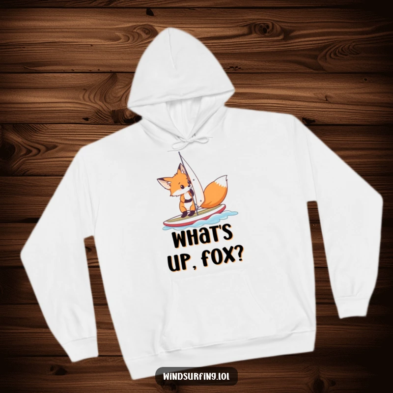 Funny fox adjusting its sail on a small surfboard, depicted on a cozy hoodie for humorous warmth and outdoor-inspired style.